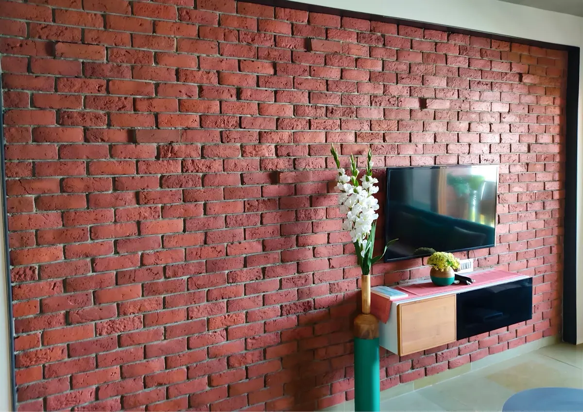 Pared interior de ladrillo visto de lámina junto a un mueble bajo y un televisor